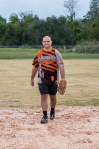 A man in a catchers mitt walking on a baseball field